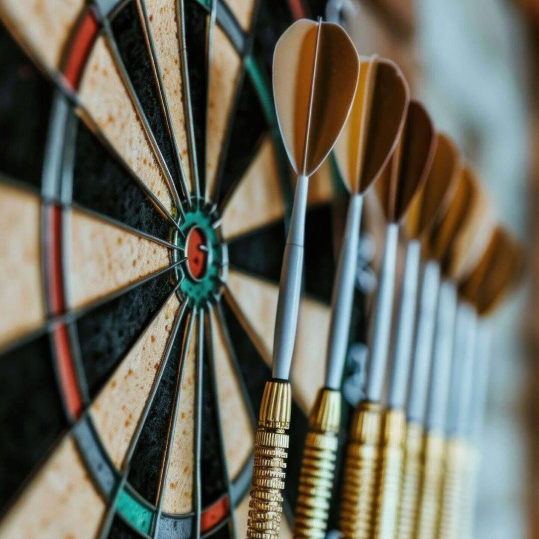 An artfully arranged dartboard with a variety of colorful darts. This indoor game of precision sports combines symmetry, patterns, and skill in hitting the bullseye on the triangular target